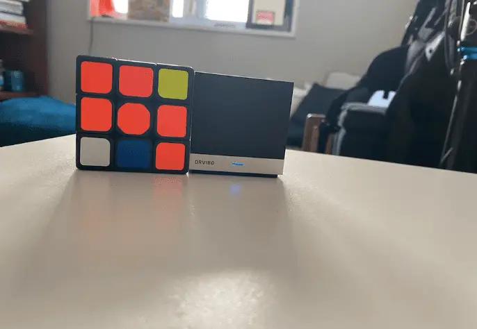 Orvibo's Magic Cube rust op een tafel naast een Rubik's Cube voor vergelijking van de grootte