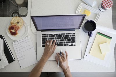 Bovenaanzicht vrouw aan het werk op laptop bij ontbijt aanrecht