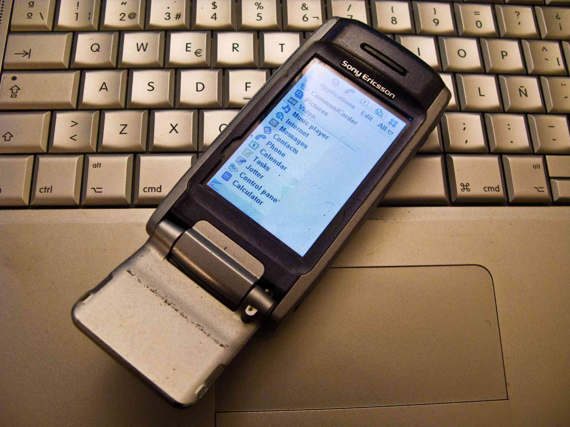Foto van een oude mobiele telefoon van Sony Ericsson op een laptop