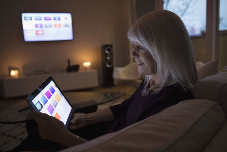 Persoon die smart TV-apps gebruikt op digitale tablet op de bank in de woonkamer