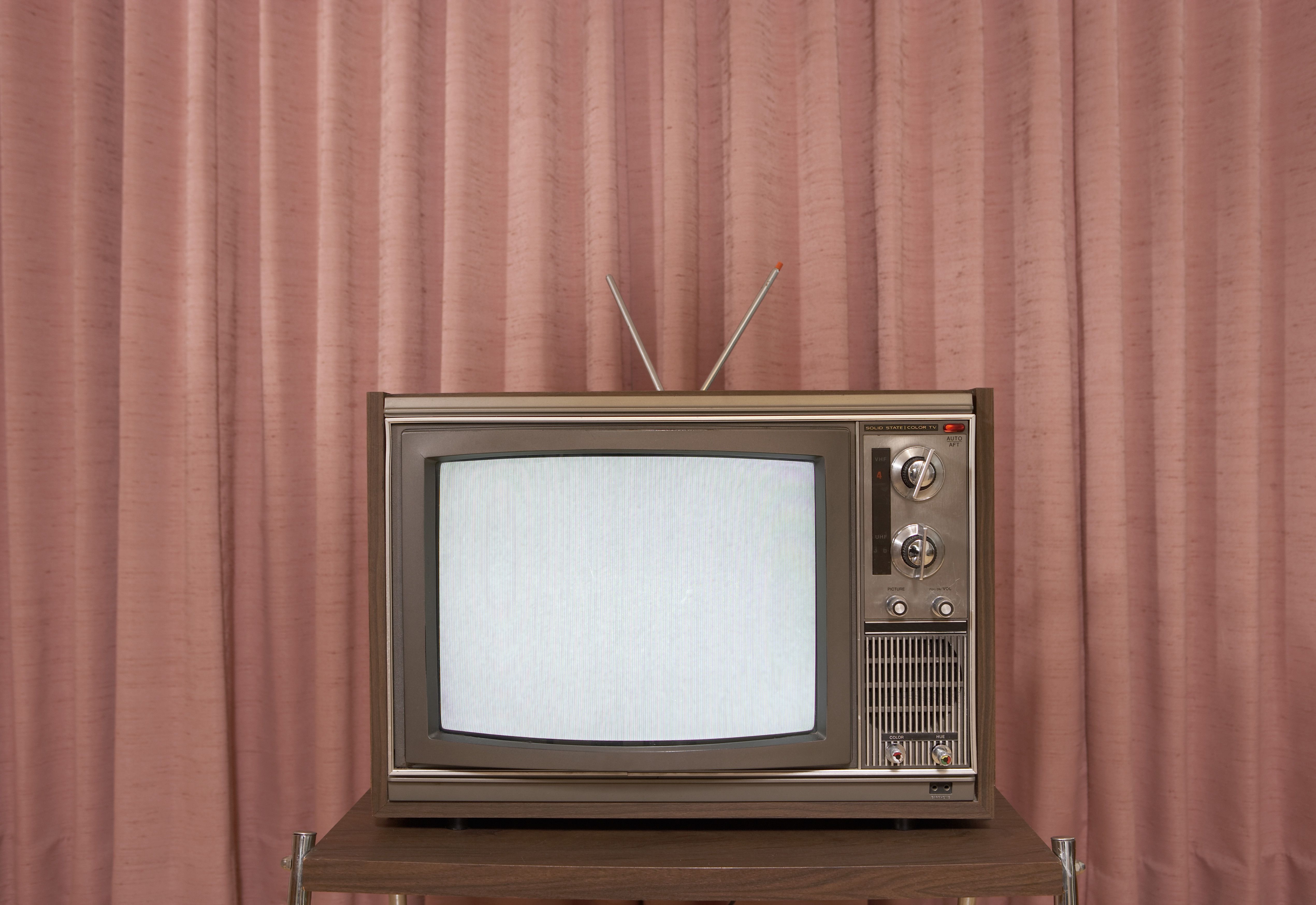 Oude televisie op standaard, voor gordijn