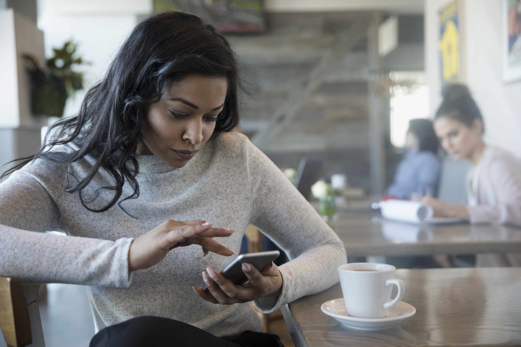 Vrouw die een iPhone gebruikt in een koffiehuis