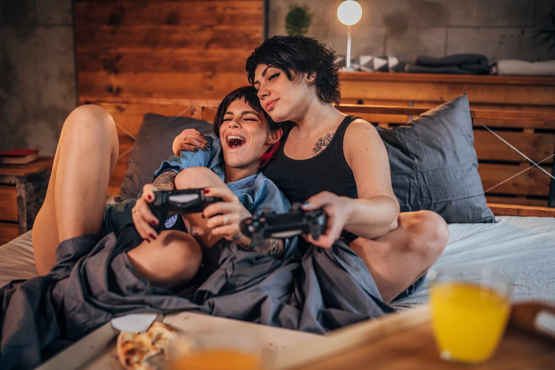 Een stel dat videogames speelt in de slaapkamer terwijl ze pizza eten. 