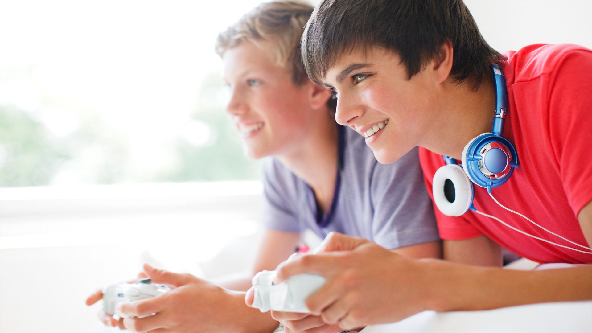 Twee tienerjongens die Xbox-videogames spelen terwijl ze op een bed liggen