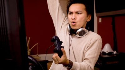 Aziatische man speelt een videogame op zijn computer met een koptelefoon om zijn nek