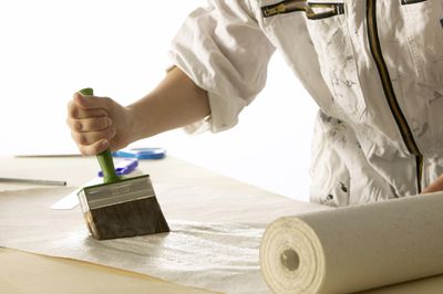 Persoon gebruikt een grote borstel om pasta op een rol papier aan te brengen.