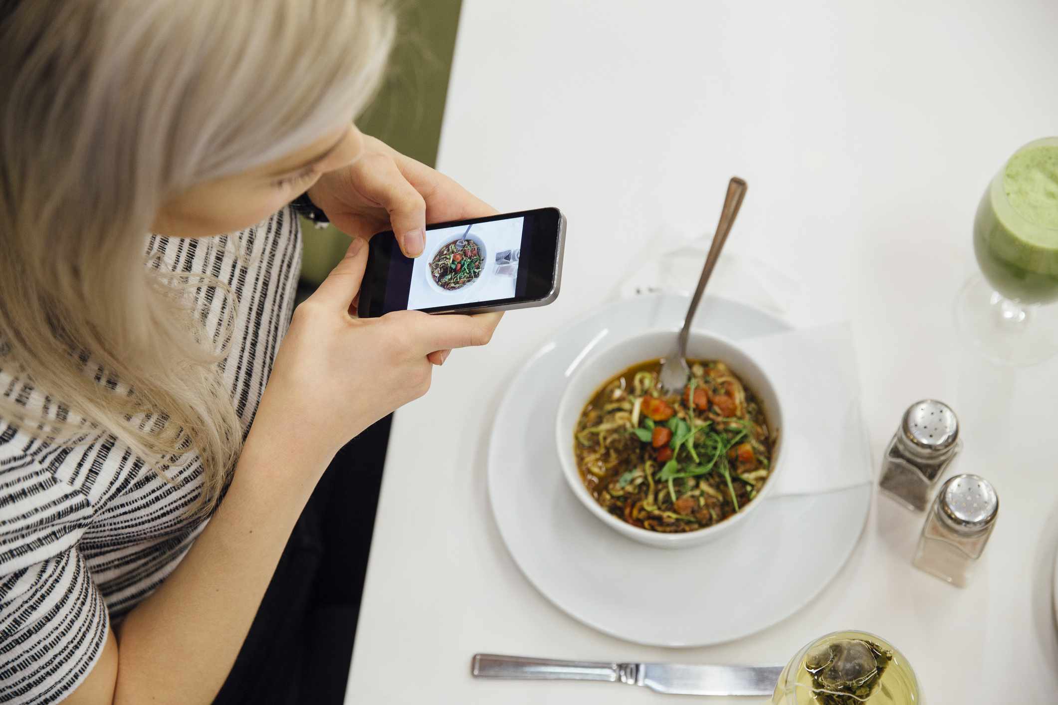 Persoon die een foto maakt van hun maaltijd op een smartphone.