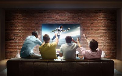 Vier mannen kijken naar een voetbalwedstrijd
