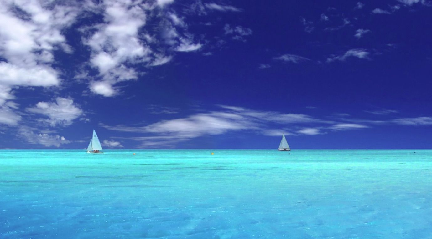 Gratis oceaanbehang met verre witte zeilboten in een lichtblauwe oceaan onder een blauwe lucht met verspreide wolken