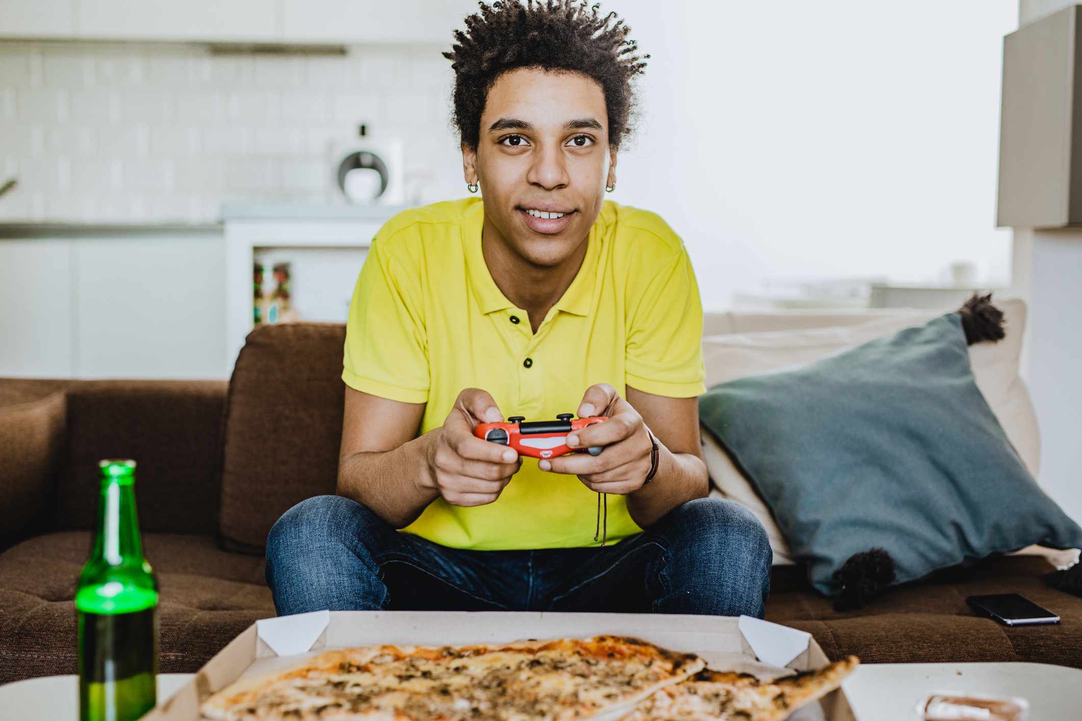 Een jonge volwassene die videogamers speelt bij een pizza en een drankje.