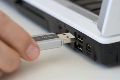 Persoon die USB-stick in een laptop steekt