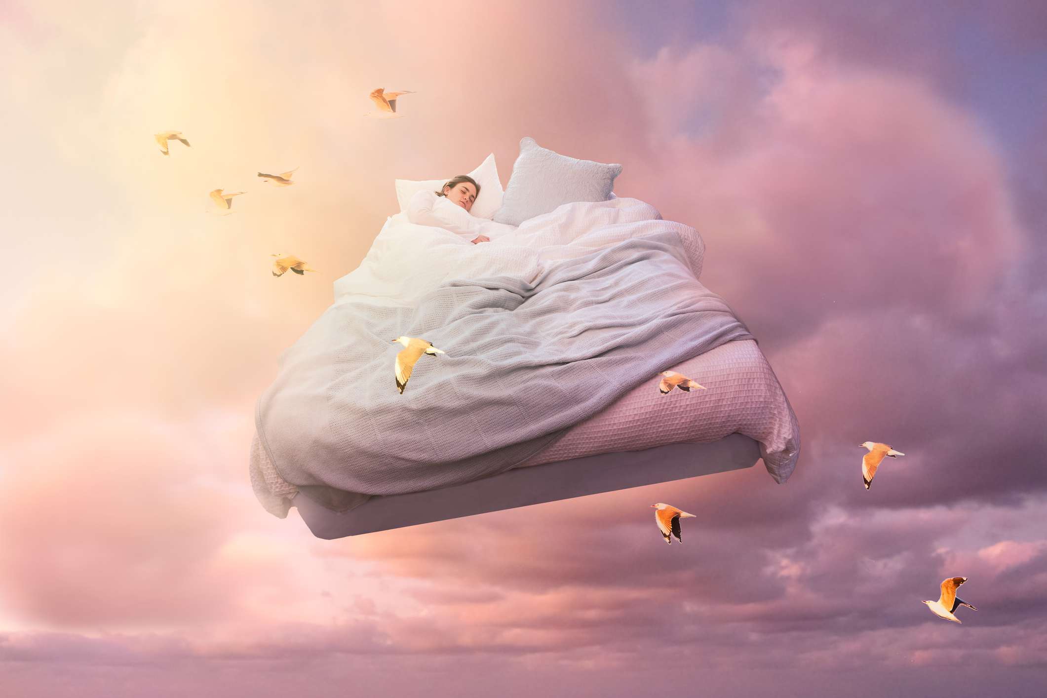Een slapend meisje zweeft op een bed in de lucht en droomt