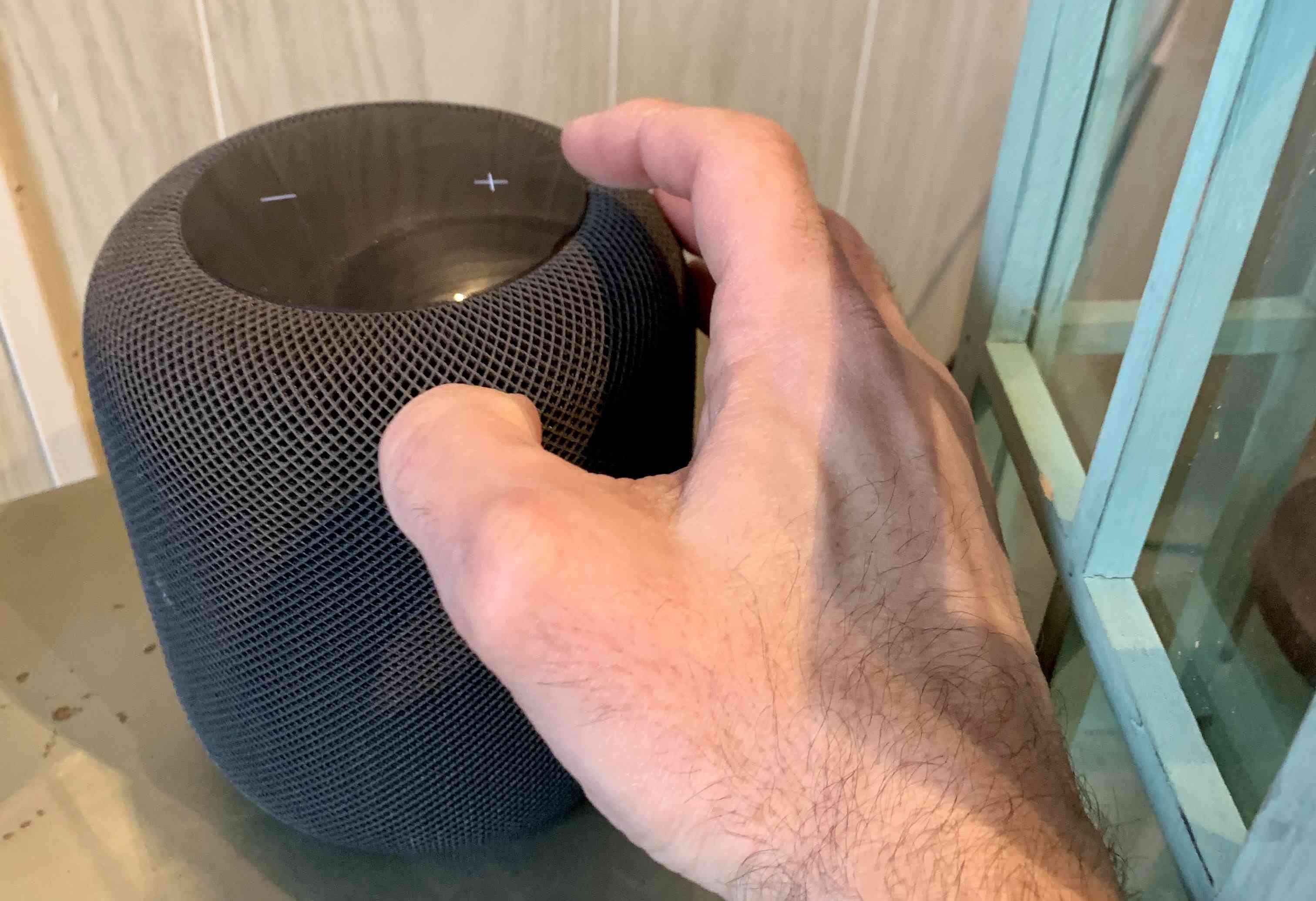 Iemand die het volume op de Apple Homepod aanpast.