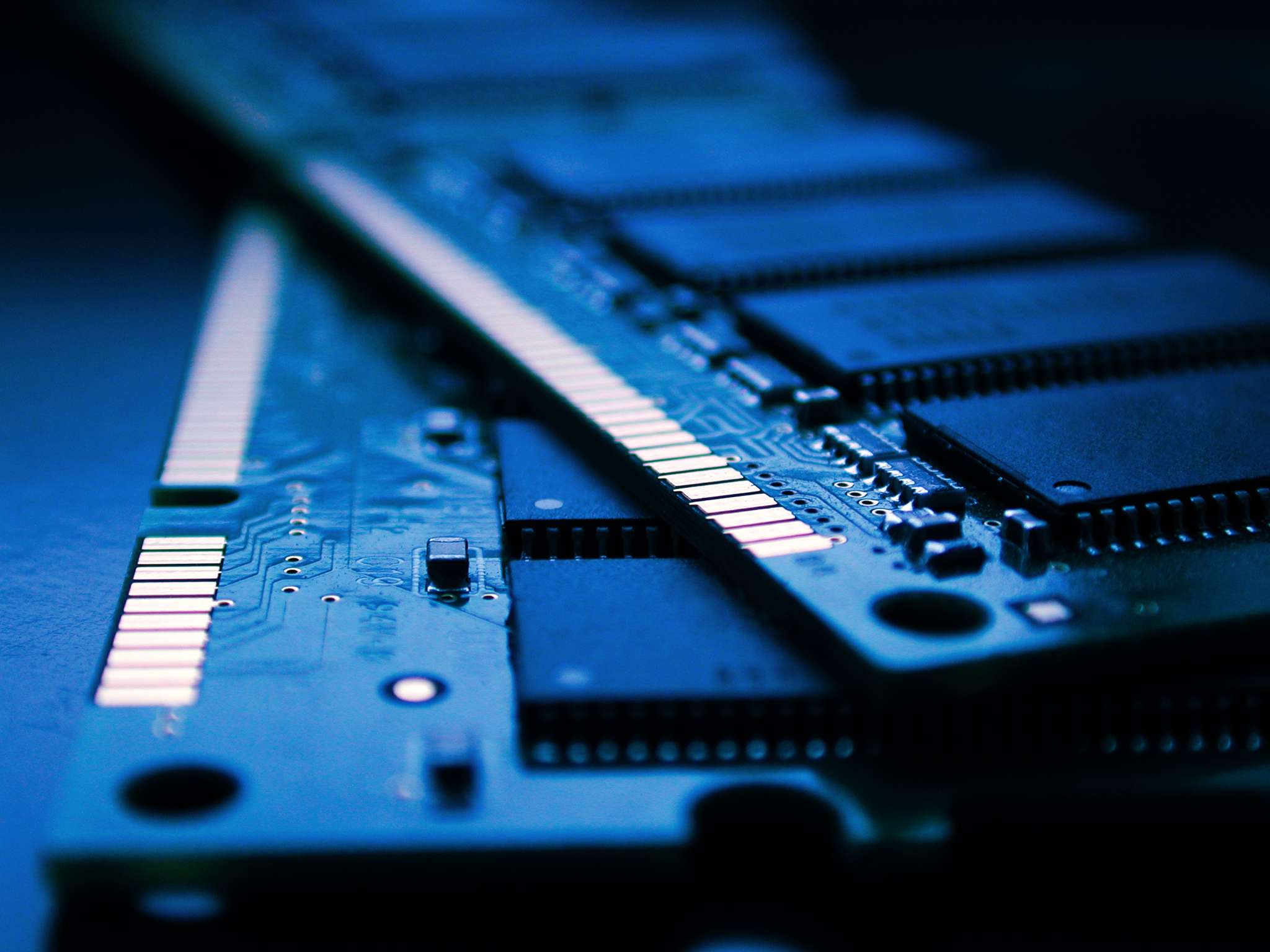 Een close-up van twee stokken computer-RAM onder een zacht blauw licht