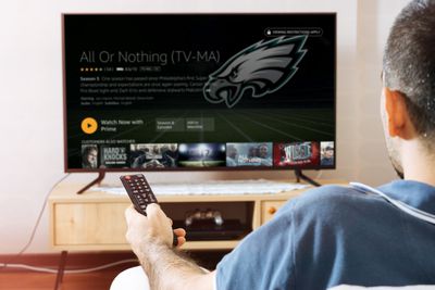 Een man kijkt naar Amazon Prime-sport op zijn televisie.