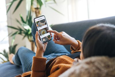 Een persoon die op een bank ligt en door zijn telefoon bladert