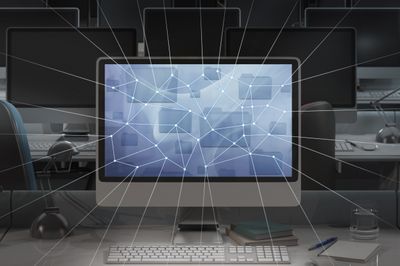 Afbeelding van een computer in een donker kantoor met netwerklijnen die uit de monitor komen