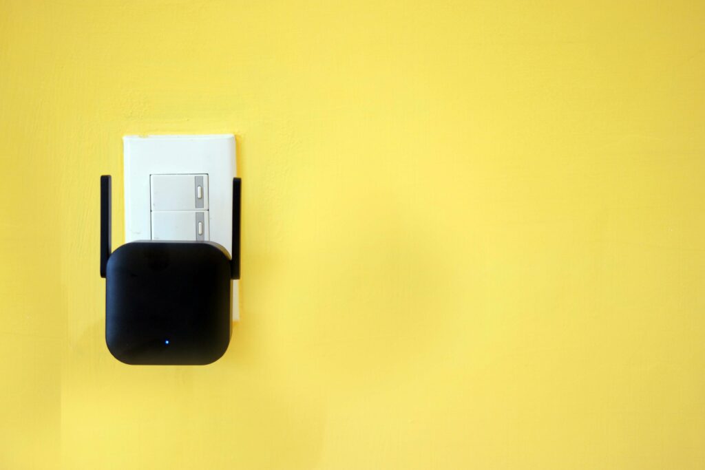 close up of wifi extender against yellow wall 1206004637 2543059f1a614f03b2d77798bc8c60b9