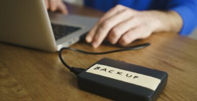 midsection of man using laptop with backup label on external hard disk drive at table 962574588 5b79f883c9e77c00572b2b8c