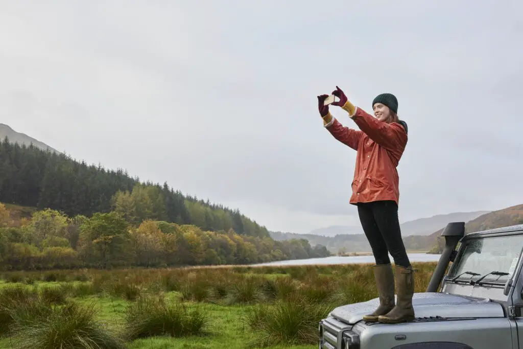 woman standing on car taking photo 690697177 5ad91adc0e23d9003673769e