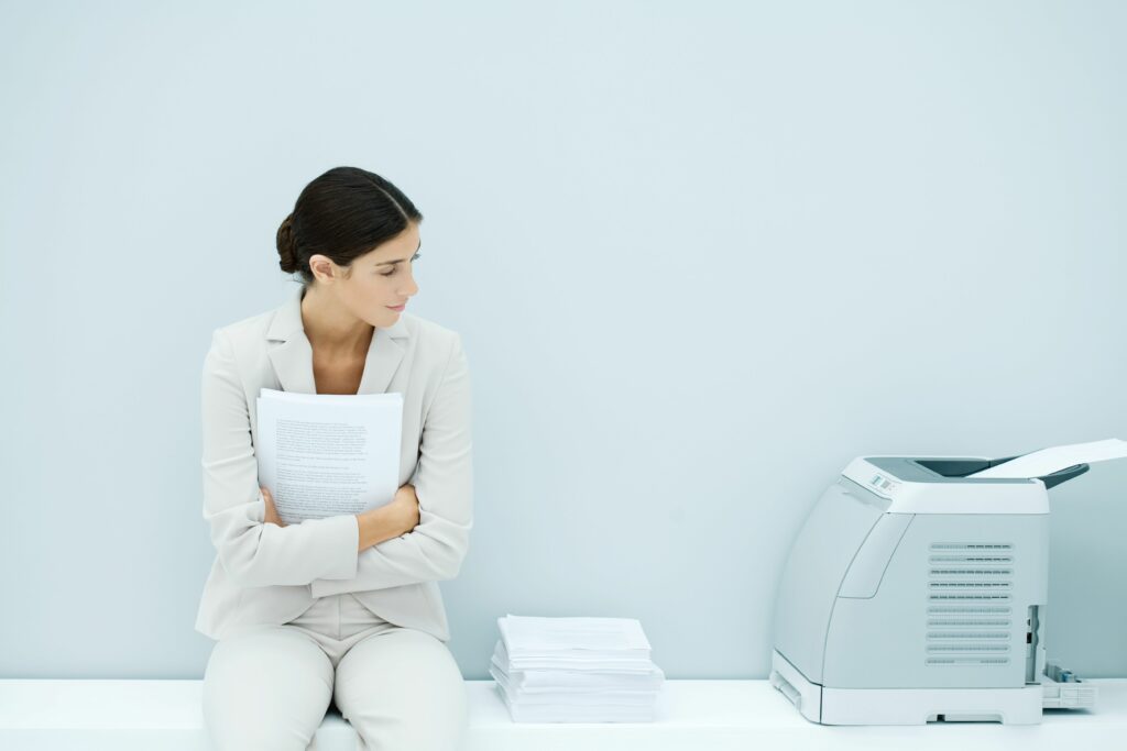 young woman in suit sitting next to printer 81737128 5b2afc9543a10300367c44f4