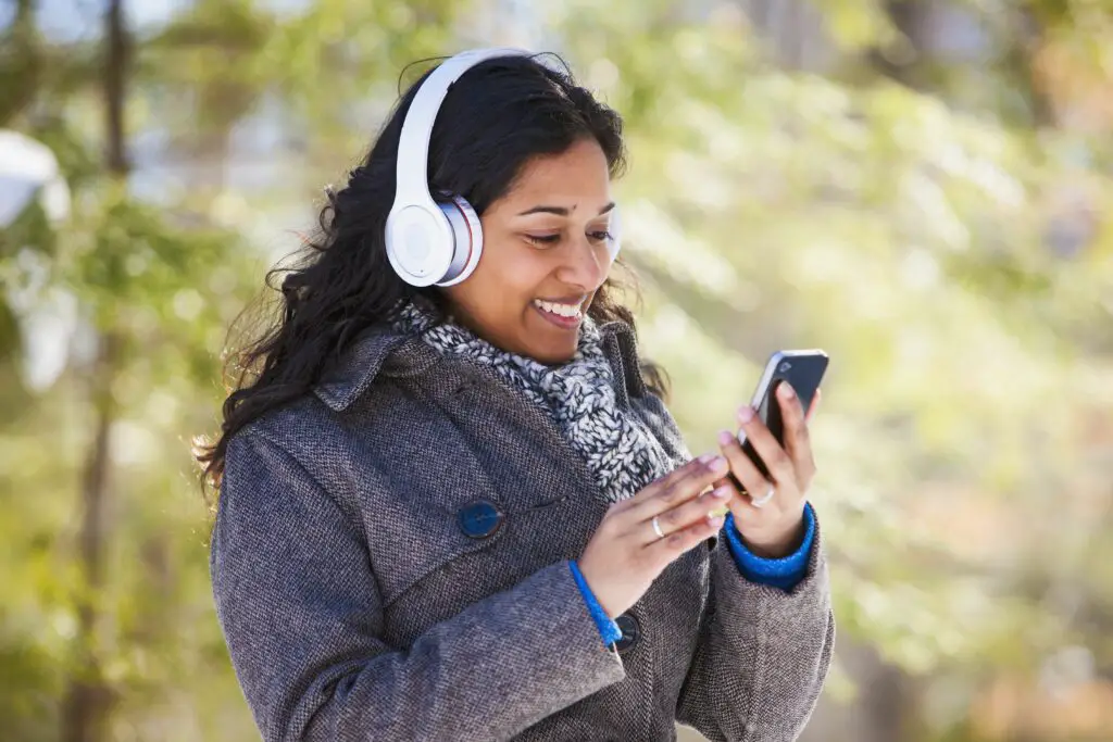 young woman of south asian ethnicity using cell phone and bluetooth headphones in scanlon creek conservation area 574897321 5a8e1095c5542e0037208303