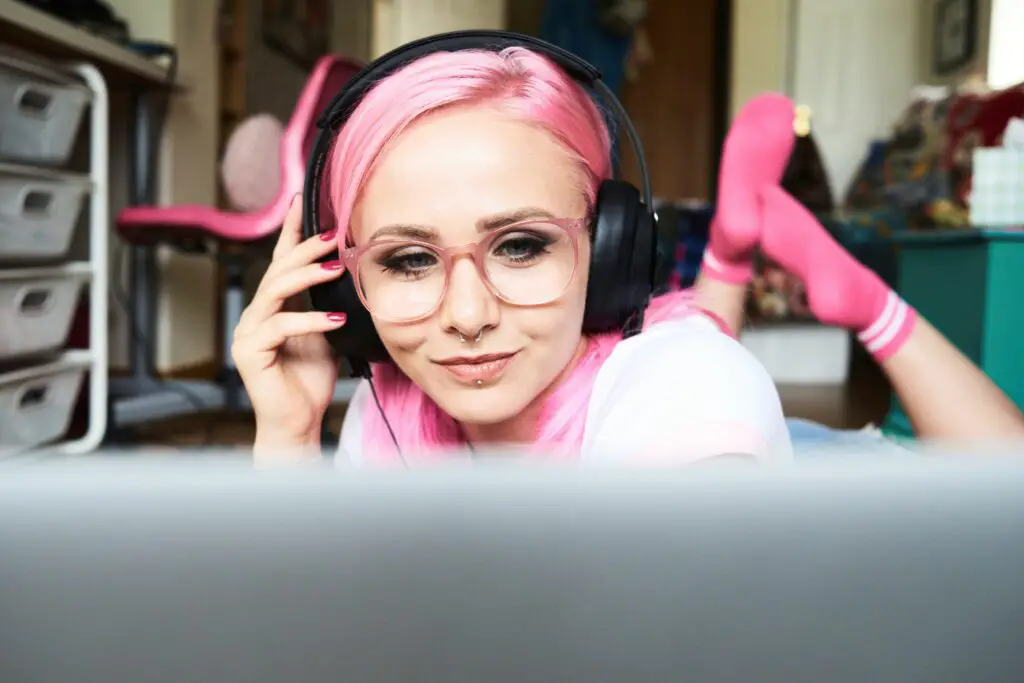 young woman with pink hair listening to music via laptop at home 769729445 5a36dfedaad52b0036c213f3 5c057421c9e77c0001694fb9