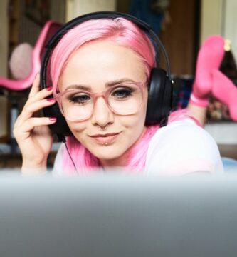 young woman with pink hair listening to music via laptop at home 769729445 5a36dfedaad52b0036c213f3 5c057421c9e77c0001694fb9