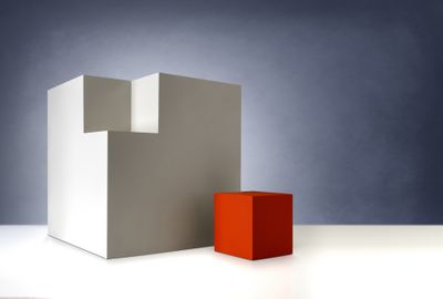 Rode kubus die in een grotere beige kubus past