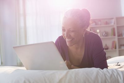 Vrouw met behulp van laptop op een bed