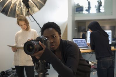 Gerichte vrouwelijke fotograaf die digitale camera gebruikt bij fotoshoot in studio