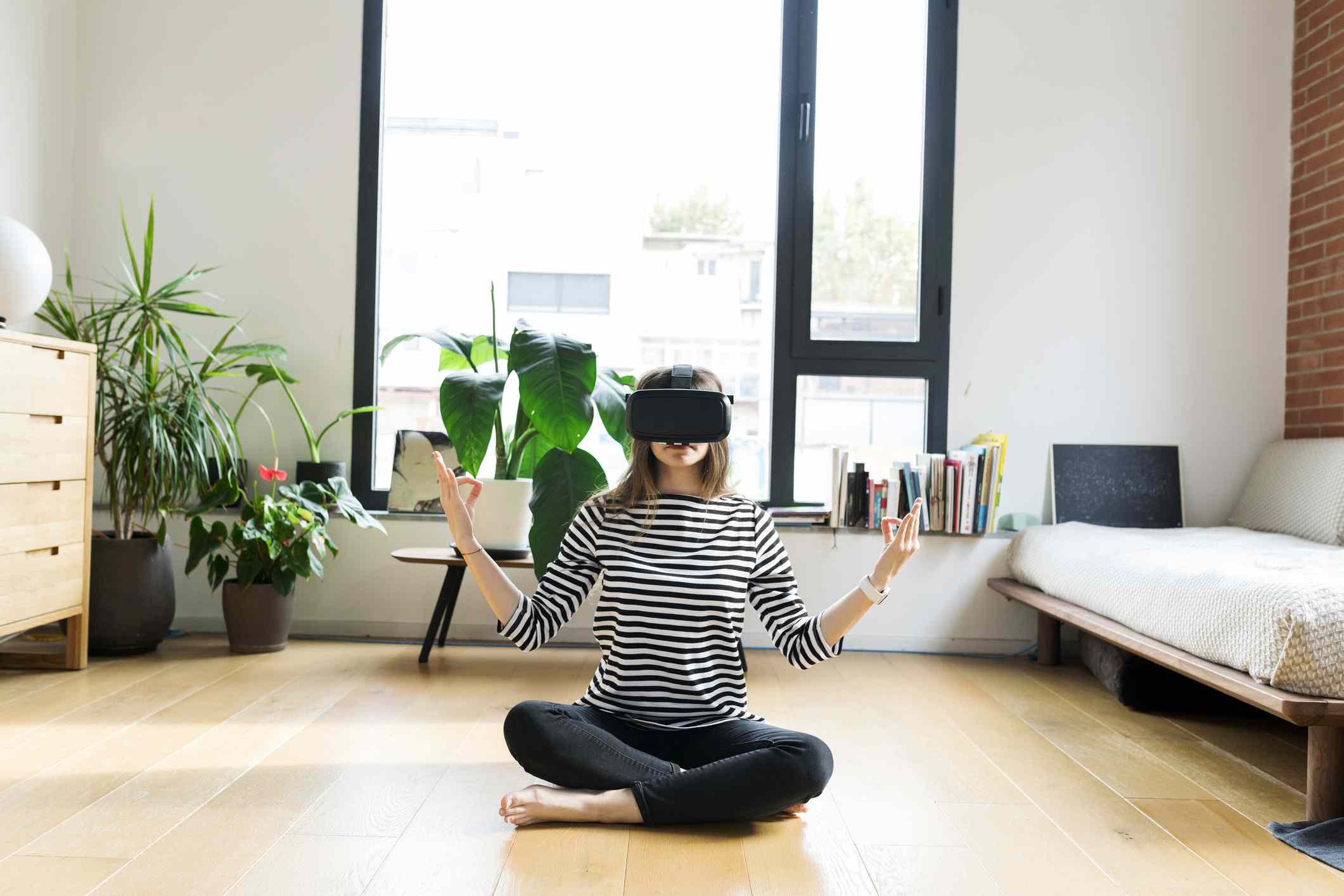 Een jongere die thuis een VR-bril draagt ​​en yoga doet.