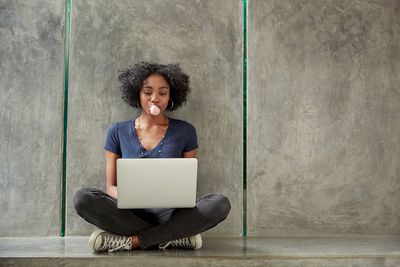 Afro-Amerikaanse student die laptop gebruikt en kauwgombel blaast