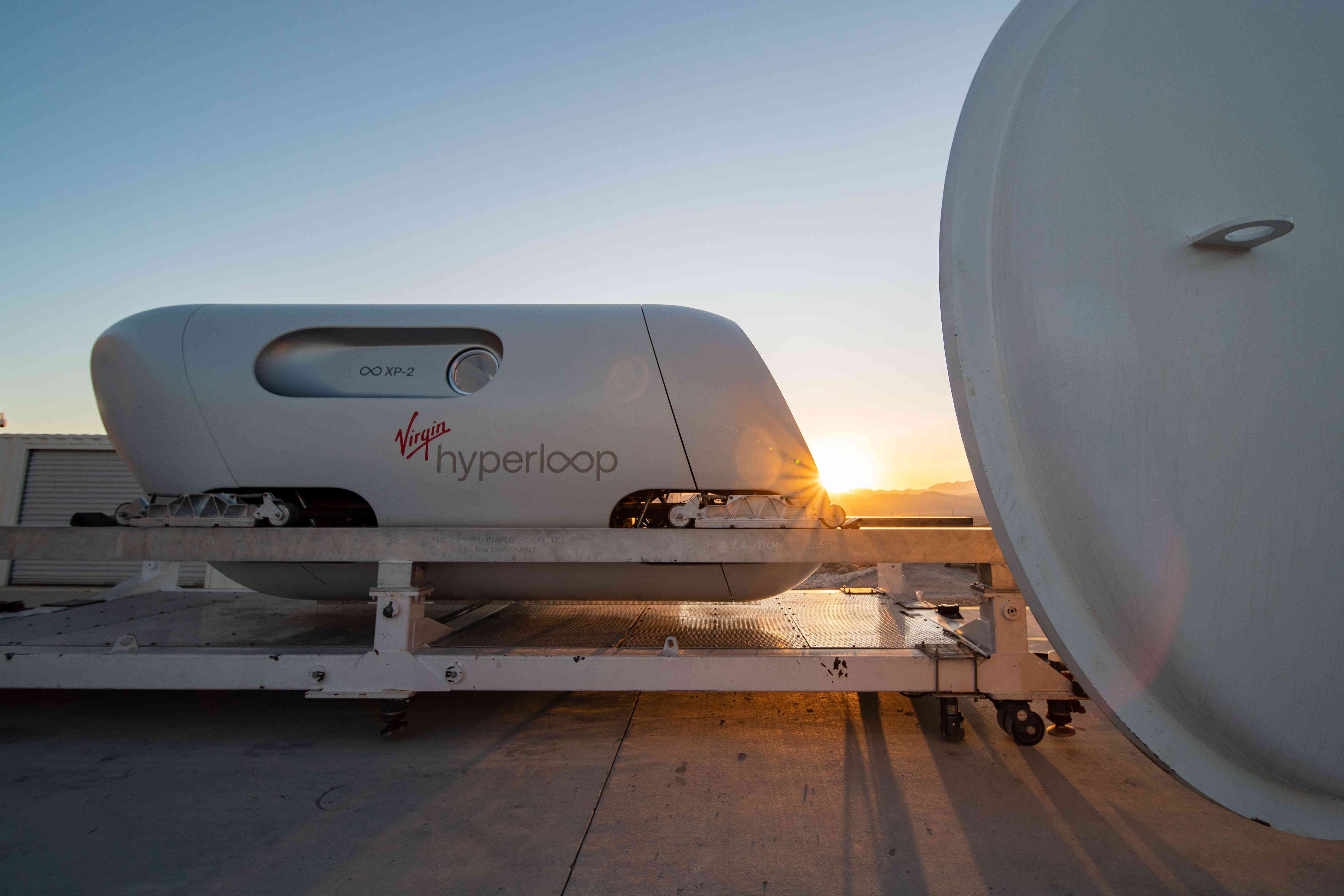 De testpod van Virgin Hyperloop rust op een platform met een zonsondergang erachter