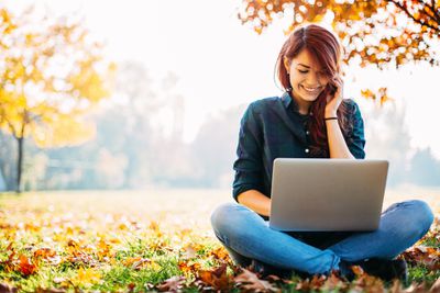 Meisje met computer tijdens de herfst