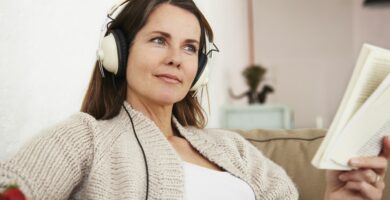 middle aged woman sitting on sofa listening to music and reading book 535257292 5b30f3eb0e23d900368df0c0
