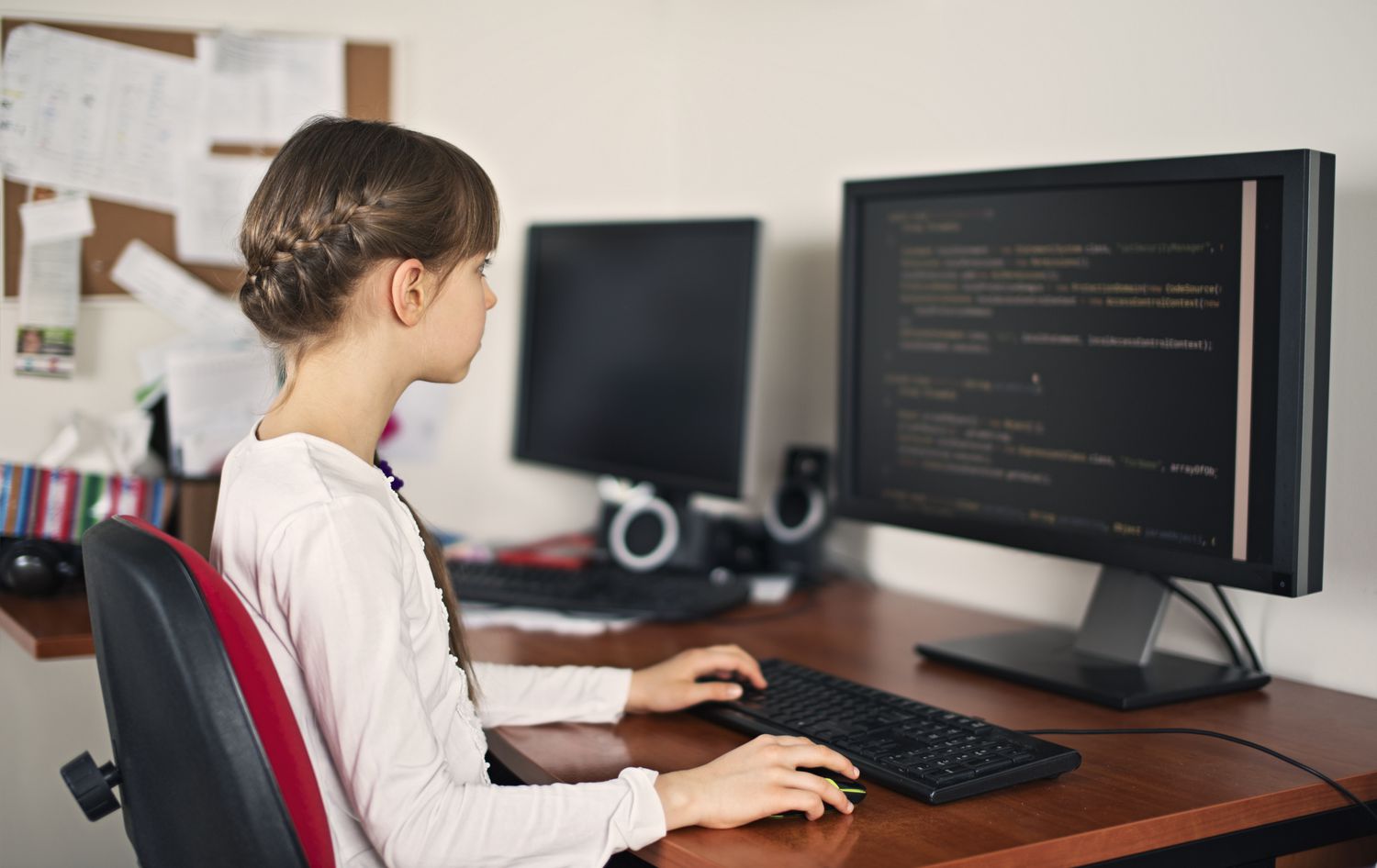 Student leert thuis coderen op een desktopcomputer