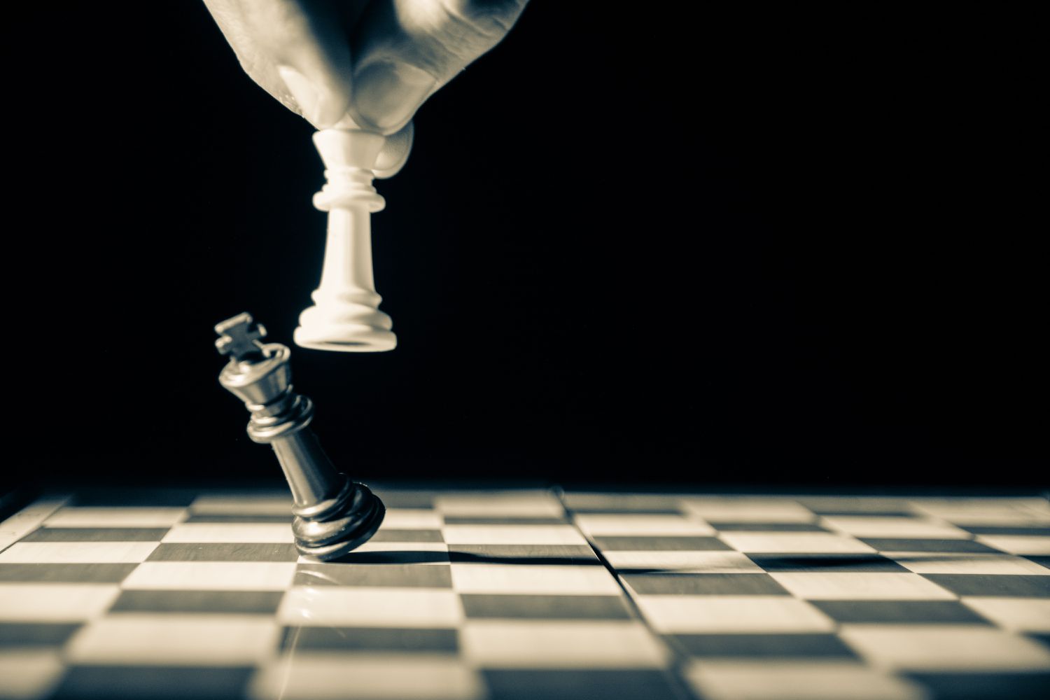 Close-up grijswaardenbeeld van een witte schaakkoning die een zwarte schaakkoning neerhaalt. 